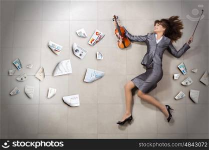 Professional in business. Attractive businesswoman with violin in hands and papers flying in air