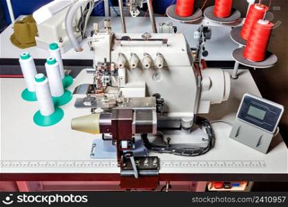 Professional industrial overlock and sewing machine with electronic control and programmable functions. Closeup.. Bright sparks and flying blue smoke during electric welding of a metal fence by a worker in leather gloves.