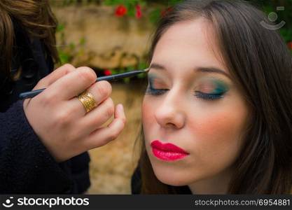 Professional make up artist doing glamour model makeup at work.