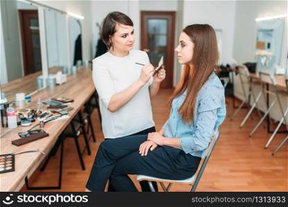 Professional makeup artist work with glamour woman in beauty studio. Cosmetic salon