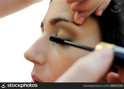 Professional makeup with a beautiful young woman having touches applied to her make up by a beautician