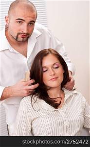 Professional male hairdresser comb female customer at salon