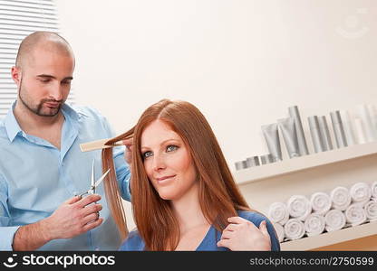 Professional male hairdresser cut with scissors at salon, female red hair customer getting new haircut