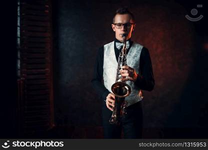 Professional male saxophonist playing jazz musical melody on saxophone. Male saxophonist playing jazz melody on saxophone