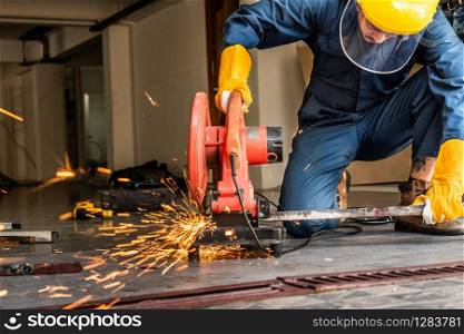 Professional mechanic is cutting steel metal with rotating diamond blade cutter. Steel industry and workshop concept.. Professional mechanic is cutting steel metal.