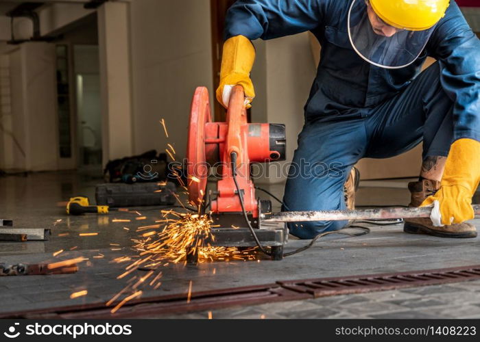 Professional mechanic is cutting steel metal with rotating diamond blade cutter. Steel industry and workshop concept.