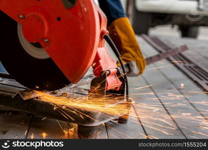 Professional mechanic is cutting steel metal with rotating diamond blade cutter. Steel industry and workshop concept.