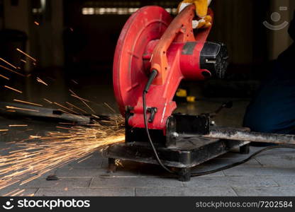 Professional mechanic is cutting steel metal with rotating diamond blade cutter. Steel industry and workshop concept.