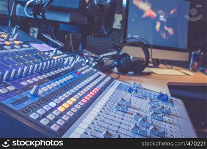 Professional music production in a sound recording studio, mixer desk and equipment in the blurry background