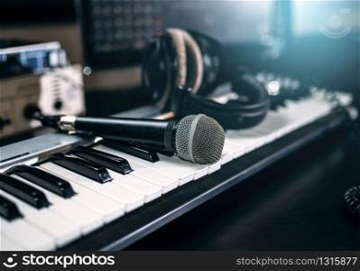 Professional music studio equipment, closeup. Musical keyboard, microphone and headphones. Audio recording tools