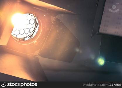 Professional orange studio spotlight hanging on the ceiling. Lighted dust particles and lens flares.