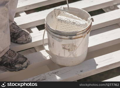 Professional Painter Rolling White Paint Onto The Top of A Home Patio Cover.