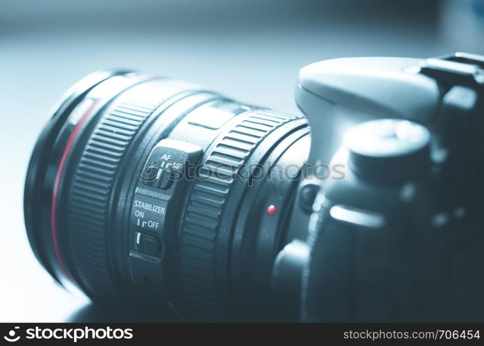 Professional reflex camera with telephoto lens on the table, cutout, blurry background