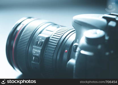 Professional reflex camera with telephoto lens on the table, cutout, blurry background