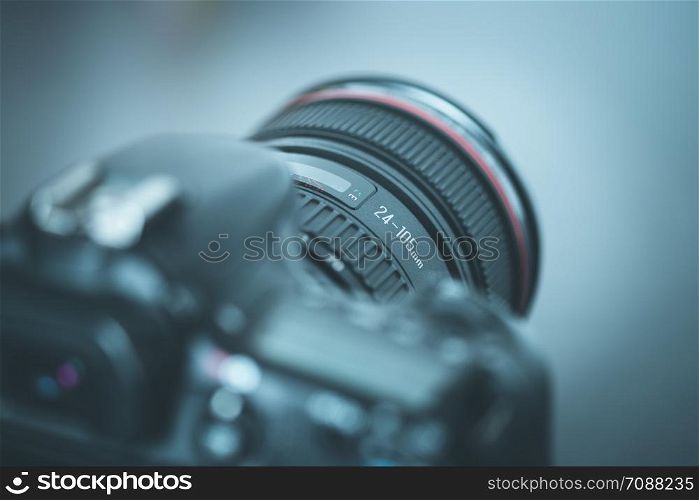 Professional reflex camera with telephoto lens on the table, cutout, blurry background