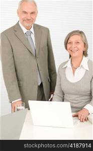 Professional senior businessman looking at computer with woman colleague