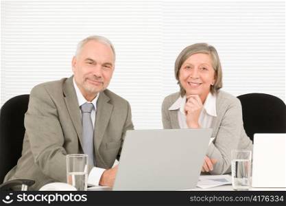 Professional senior businessman pointing at computer with woman colleague discussing