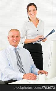 Professional senior businessman sitting in office with woman secretary