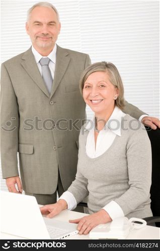 Professional senior businesswoman behind computer with male colleague