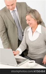 Professional senior businesswoman looking at computer with man colleague