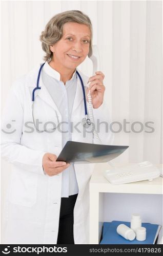 Professional senior doctor female on phone hold x-ray at office