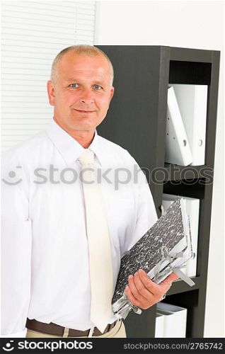 Professional senior mature businessman standing in office holding folders