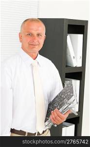 Professional senior mature businessman standing in office holding folders