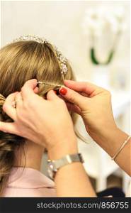 Professional services in the hairdressing salon - a young woman with beautiful blonde hair has made hairstyles for a wedding party.
