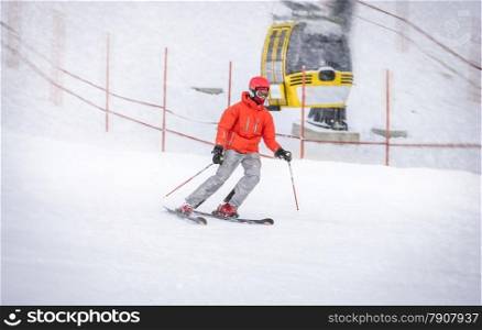 Professional skier in red jacket going down the hill fast