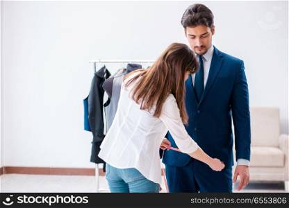 Professional tailor taking measurements for formal suit