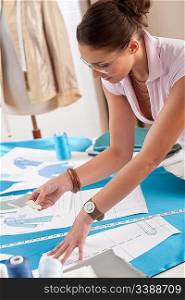 Professional tailor working with fashion sketches at studio