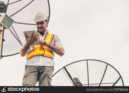 Professional technician or engineer standing on roof top of building working with satellite dish. Concept of repair installation service and telecommunication.