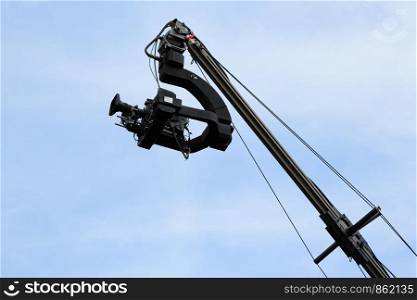 Professional TV camera on a crane against sky.