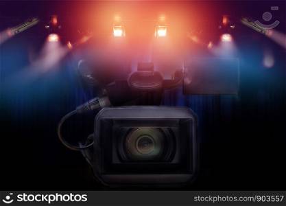 professional video camcorder with set of light hanging in television studio background.