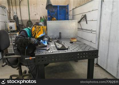 Professional welder performs work with metal parts in factory, sparks and electricity. Industry worker banner. High quality photo. Professional welder performs work with metal parts in factory, sparks and electricity. Industry worker banner.