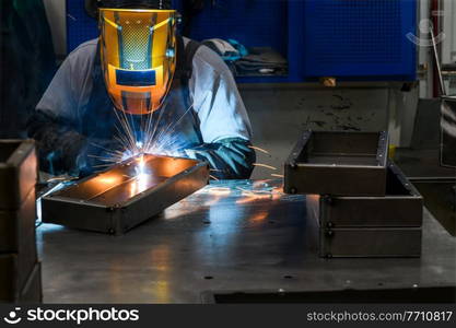 Professional welder performs work with metal parts in factory, sparks, and electricity. Industry worker banner. High quality photo. Professional welder performs work with metal parts in factory, sparks and electricity. Industry worker banner.