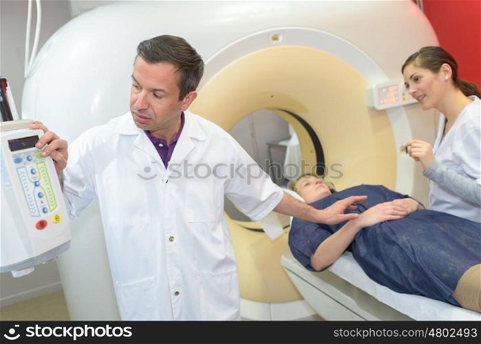 professional with patient and doctor using cat scan