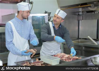 Professional workers seasoning meat