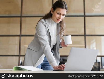 professional young smiling businesswoman holding coffee cup white working laptop