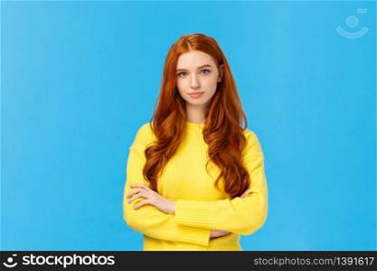 Professionalism, e-commerce and business concept. Serious-looking determined smart gorgeous redhead woman in yellow sweater, cross arms chest confident, looking camera, blue background.. Professionalism, e-commerce and business concept. Serious-looking determined smart gorgeous redhead woman in yellow sweater, cross arms chest confident, looking camera, blue background