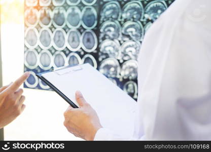 Professor Doctor discussion a method with patient treatment, with Mammogram film x-ray of patient 's head for brain, skull or eye injury and laptop computer on table.