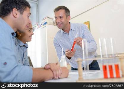 professor holding tube with orange liquid