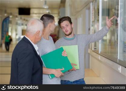 professor with notebook talking to a student in corridor
