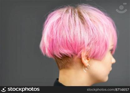 Profile of a beautiful young caucasian woman with short bob pink hairstyle on dark gray background. Profile of a beautiful young caucasian woman with short bob pink hairstyle on dark gray background.