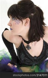 Profile of a beautiful young woman in purple and green. Purple make-up and face beads.