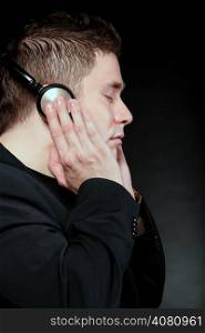 Profile of a man student with headphones listening to music closed eyes black grunge background