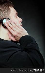 Profile of a man student with headphones listening to music closed eyes black grunge background