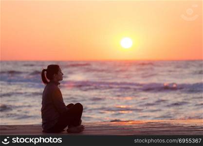 Profile of a woman silhouette watching sun on the beach at sunset