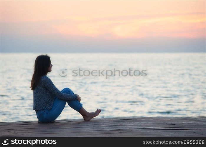 Profile of a woman silhouette watching sun on the beach at sunset