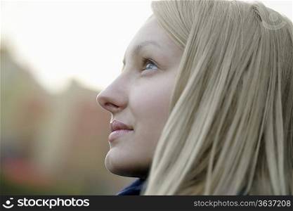 Profile of blonde woman outside looking up
